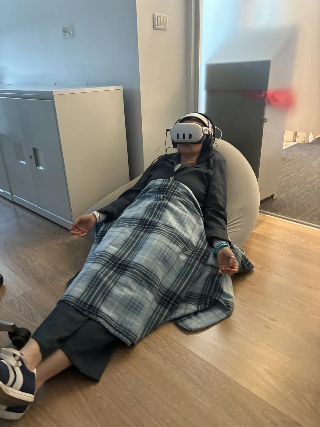 משתתפת עטופה בשמיכה על פוף במהלך חוויית VR