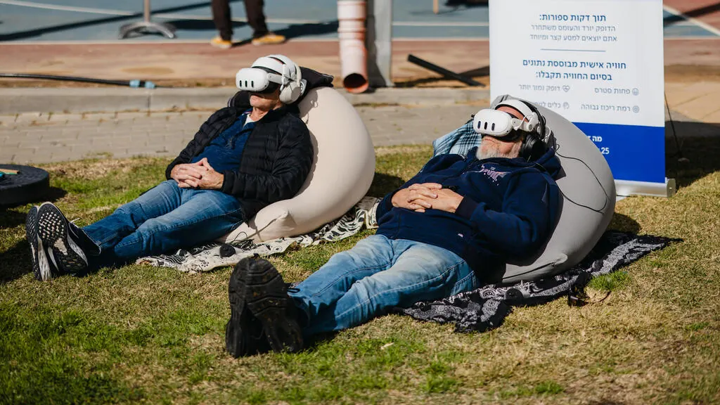 שני משתתפים עם משקפי VR נחים על פופים בפעילות וולנס בחוץ